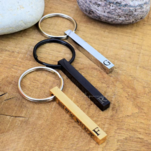 A silver metal bar keychain with a name and a heart engraved on it.