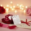 Personalized calendar keychain with engraved date and name charm placed on rose petals with romantic lights