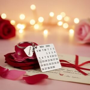 Personalized calendar keychain with engraved date and name charm placed on rose petals with romantic lights