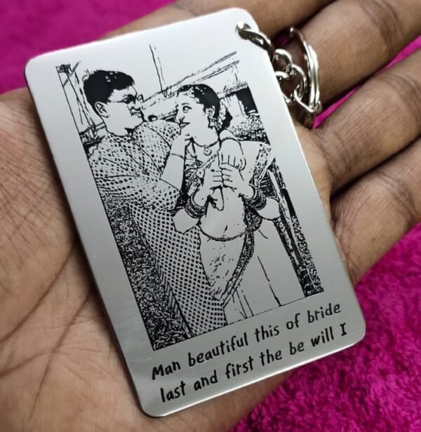 A metal pendant with a photo and text engraved on it attached to a metal key ring.