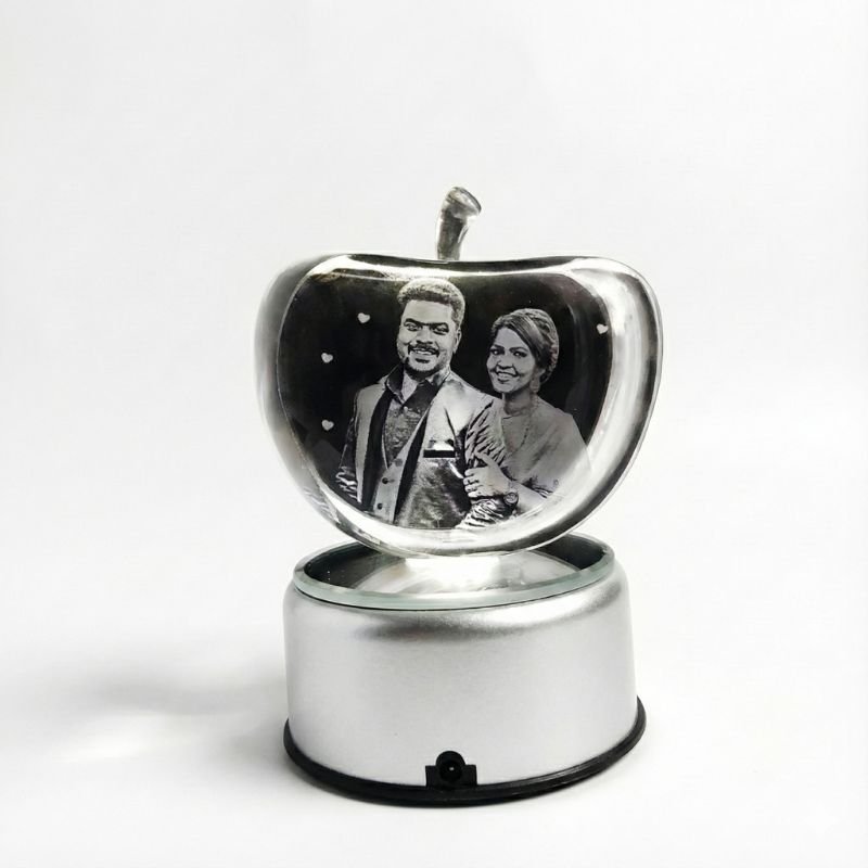 Apple crystal engraved couple portrait with colorful RGB light beams in dark background, customized romantic gift decor.