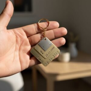 Custom couple keychain with square metal plates and engraved relationship dates, photographed on a black background