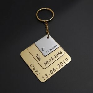 Customized metal couple keychain with layered square design and engraved anniversary dates on a dark studio background