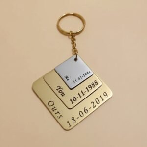 Hand holding a personalized metal couple keychain with engraved dates and “You & Me” text, showing real size and finish