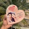 Hand-held personalized wooden heart plaque featuring a portrait of a couple, with Valentine's Day wishes and a love quote.