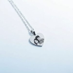 Heart-shaped stainless steel photo engraved pendant held in hand – personalized couple necklace gift