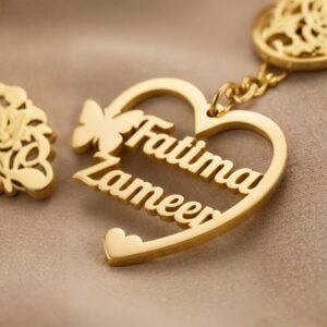 Close-up view of personalized gold heart name keychain showing engraved names and butterfly design