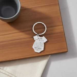 Custom date calendar keychain with engraved name and special date, displayed on a wooden tray with minimal lifestyle setup.